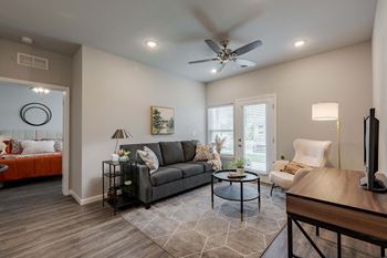 A living room with a black couch, a coffee table, and a ceiling fan.